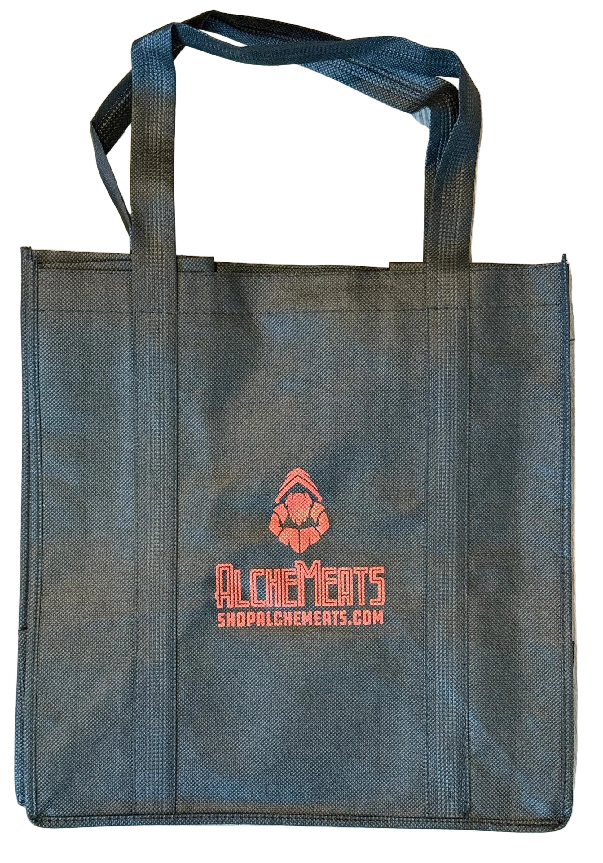 Black AlcheMeats tote bag with red logo and text on a wooden floor