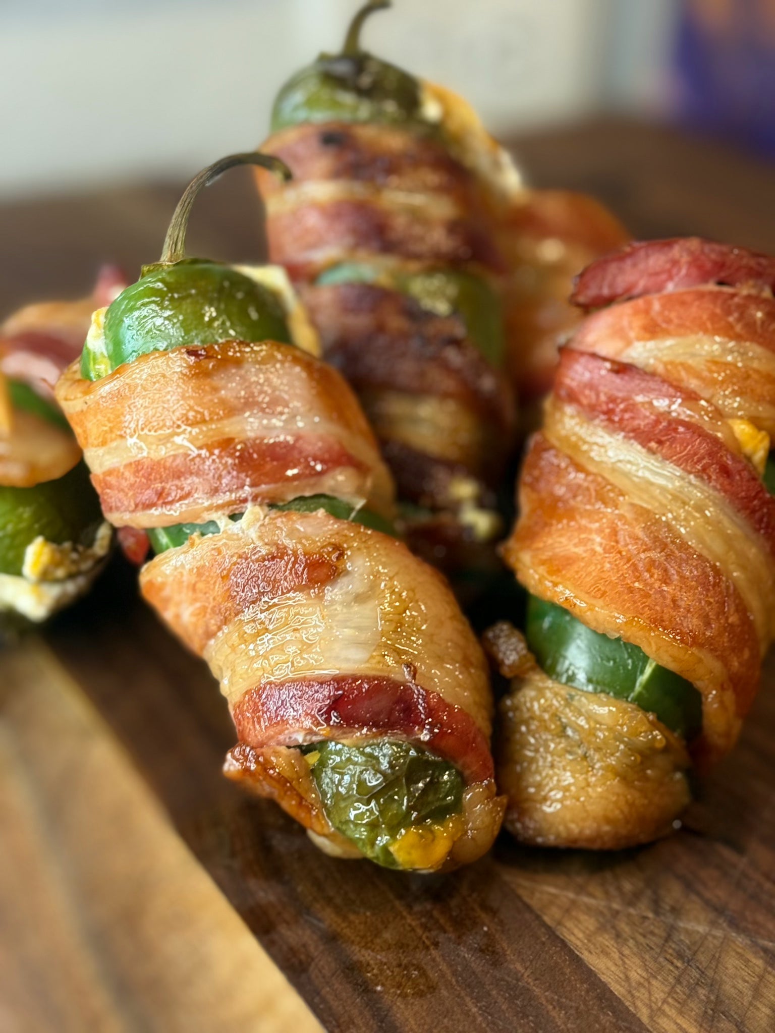Bacon-wrapped jalapeño peppers on a wooden surface